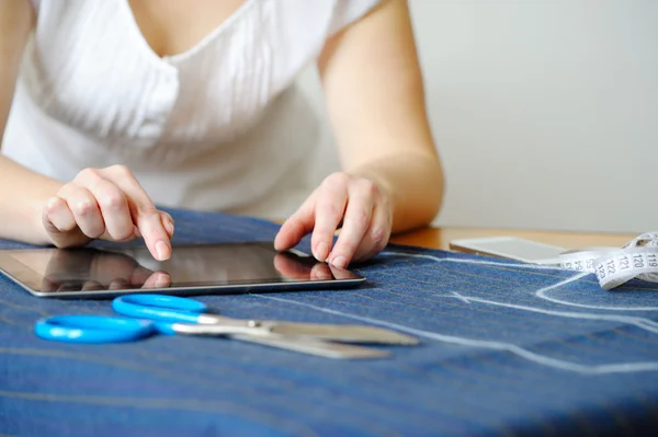 Tailoring of natural wool. Woman tailors using tablet.