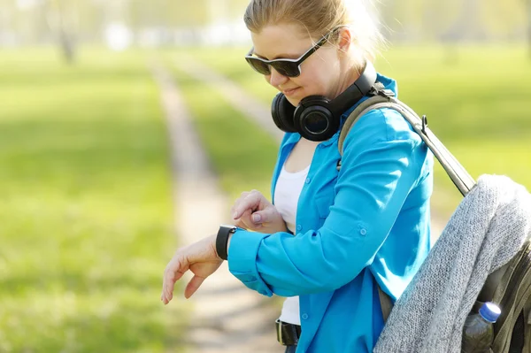 Woman with backpack on the shoulders uses of smart watches.