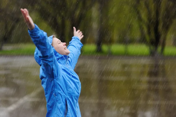 Happy woman standing with arms outstretched in rain.