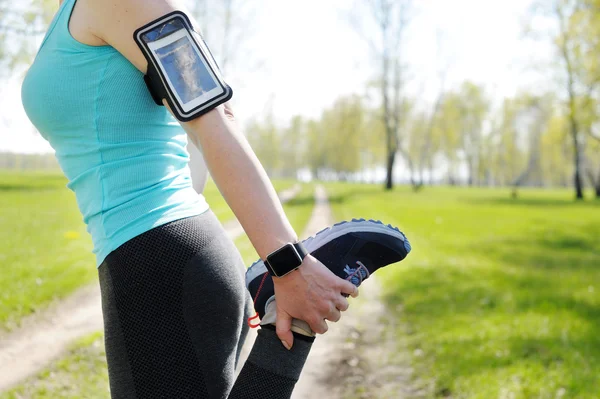 Running stretching - runner wearing smartwatch. Closeup of runni