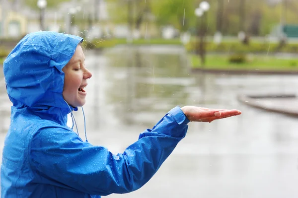 Happy woman standing with arms outstretched in rain.