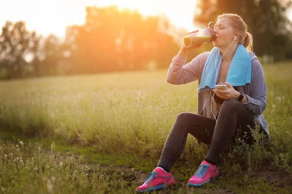 Beautiful fitness woman taking a break outside in summer fitness