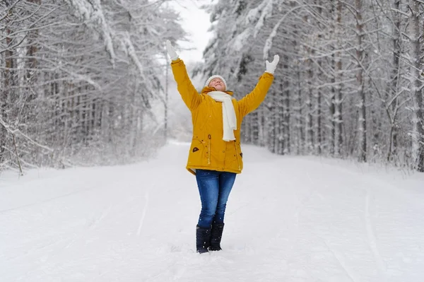 Beautiful woman in winter forest rejoices in the snow.