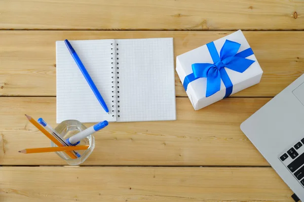 Gift with a blue ribbon on a wooden Desk in the office.