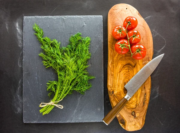 Dill on slate plate with tomatoes on side.