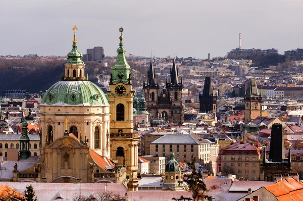 Amazing St. Nicolas church during winter day after heavy snow storm with snow cover at roofs. Sunny winter day in Old town district, Prague, Czech republic.