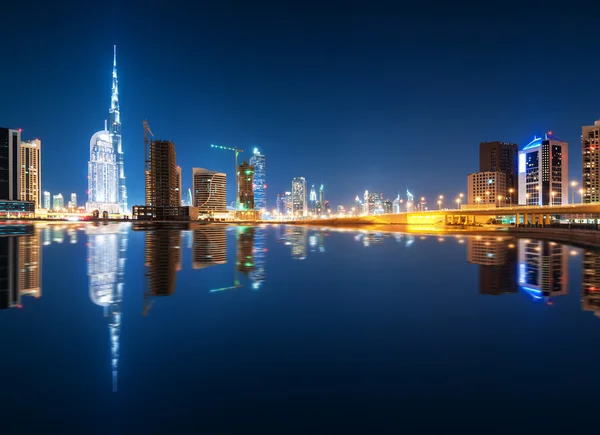 Fascinating reflection of tallest skyscrapers in Business Bay district during calm night. Downtown summer night. Construction built at night time. Dubai, United Arab Emirates.