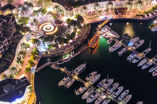 Amazing colorful dubai marina fountain and yacht dock during night. Beautiful sidewalk among tallest skyscrapers of the world. Dubai marina, United Arab Emirates.