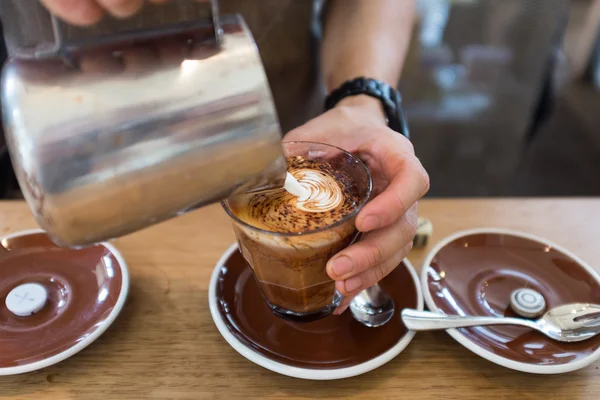 Barista pouring leaf pattern on a cappuccino coffee