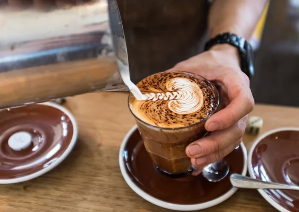 Barista pouring leaf pattern on a cappuccino coffee