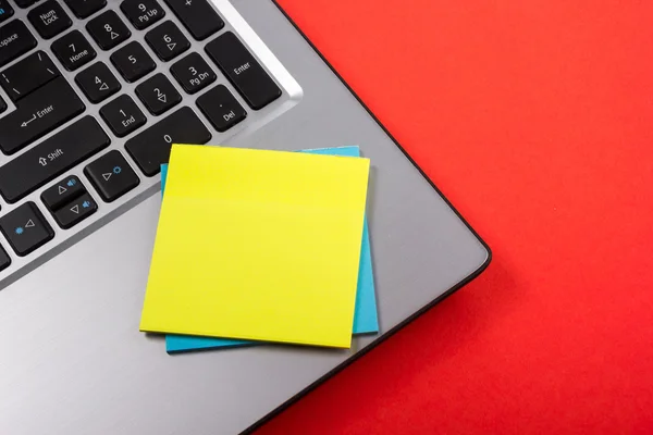 Office table desk with set of colorful supplies, white blank note pad, cup, pen, pc, crumpled paper, flower on red background. Top view and copy space for text