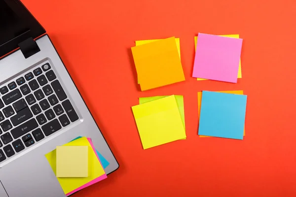 Office table desk with set of colorful supplies, laptop and reminder on red background. Top view. Copy space for text