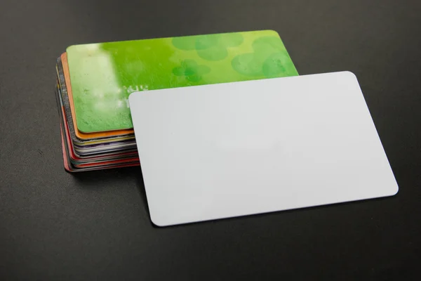 White blank business card. Office table desk with set of colorful supplies, cup, pen, pencils, flower, notes, cards on black board desk table background. Top view and copy space for ad text