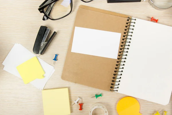 White blank open note book. Office table desk with set of colorful supplies, cup, pen, pencils, flower, notes, cards on beige desk table background. Top view and copy space for ad text