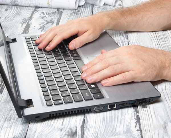 Mans hands typing laptop keyboard making online payment at home against the wooden table. On-line shopping concept. Selective focus, computer pc