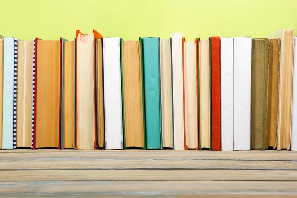 Colorful composition with vintage old hardback books stacking, diary on wooden deck table and green background. Back to school. Copy Space. Education.