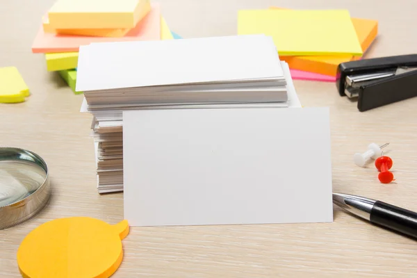 White blank business card. Office table desk with set of colorful supplies, cup, pen, pencils, flower, notes, cards on beige   background. Top view and copy space for ad text