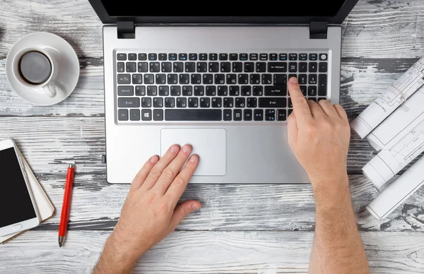 Mans hands typing laptop keyboard making online payment at home against the wooden table. On-line shopping concept. Selective focus, computer pc