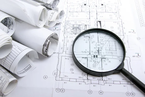 Architectural blueprints and blueprint rolls with magnifying glass