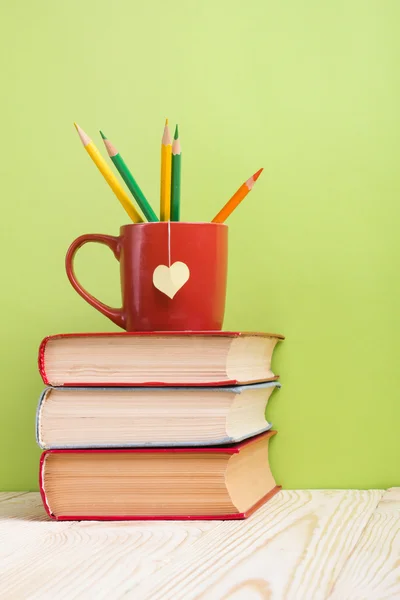 Composition with old vintage hardback books and red cup with yel