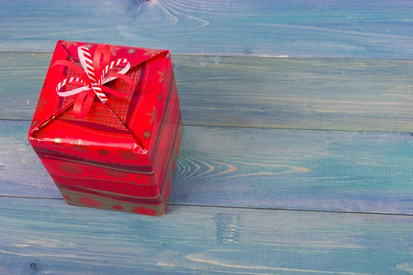 Gift box with red bow on vintage blue wooden table background. Christmas decoration on grunge blue artistic painted background. Winter holidays concept. Copy space. Merry Christmas and Happy New Year!