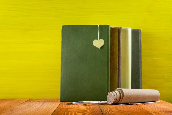 Row of colorful hardback books on yellow background.