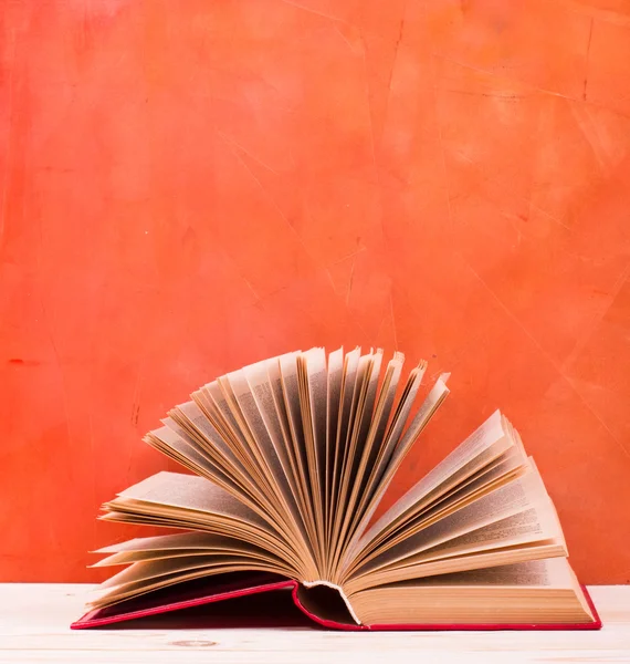 Open book, diary with fanned pages on red background.