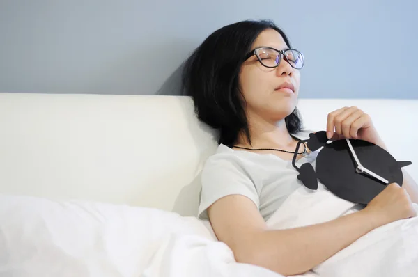 Asian woman be sleep  with black alarm clock  on a bed.