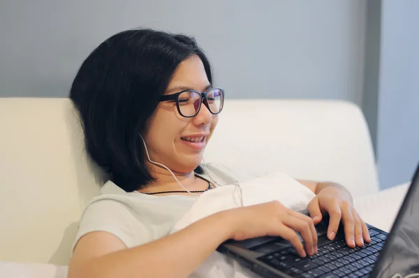 Asian woman be happy her laptop on a bed.