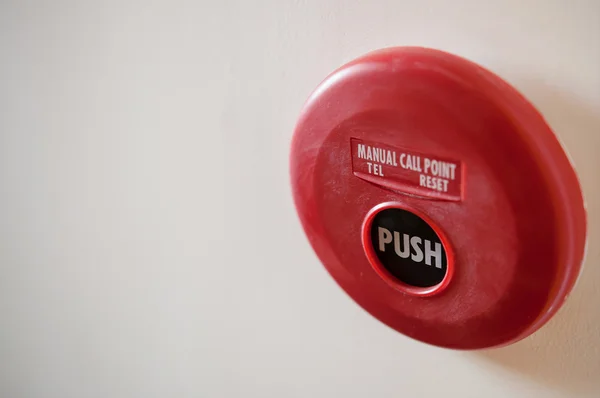 Red fire alarm and dirt on white wall background.
