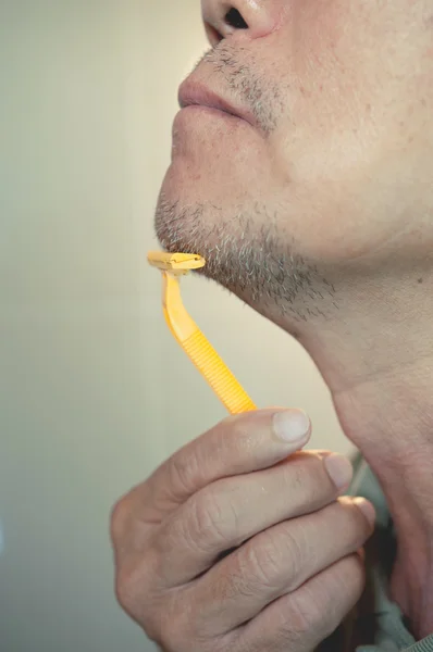 Asian old man is shaving his beard