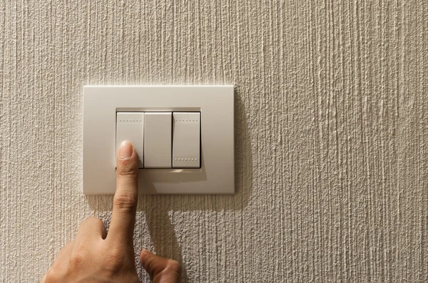 Closeup of A finger is turning on a lighting switch.