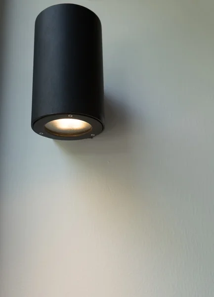 Black wall lamp on white wall.