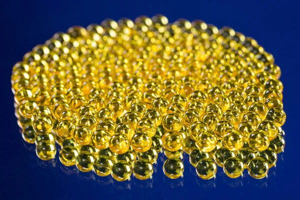 Yellow medical capsules on a mirror surface