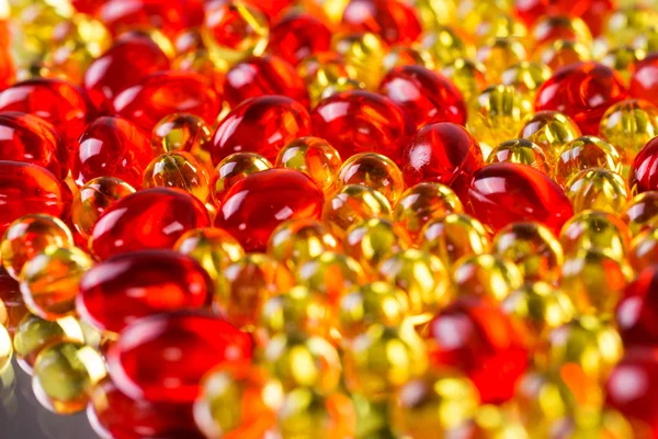 Yellow and red medical capsules on a mirror surface