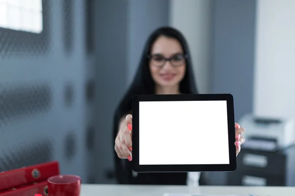 Young business woman in office holding a tablet and smiling
