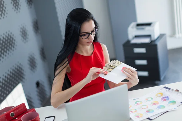 Young business woman holding money in envelope