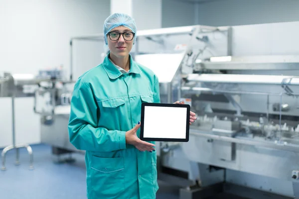 Pharmaceutical factory worker with a tablet in his hands shows Equipment