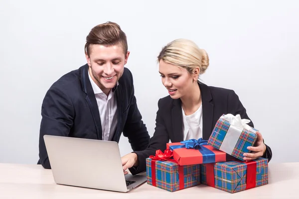 Man and woman in business suits sitting at a desk in front of la