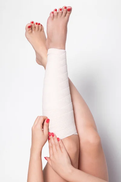 Girl on a white background corrects an elastic bandage which tie
