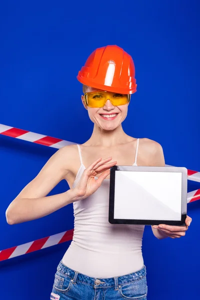 Pretty blond girl in an orange construction helmet and protectiv
