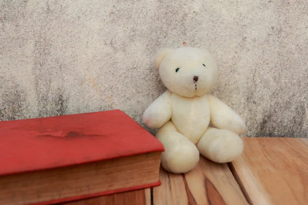 Book, teddy Bear on wooden and background of old wall. Soft focu