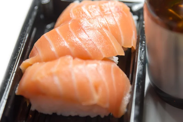 Salmon sushi closeup put bottle of food supplements nearby isol