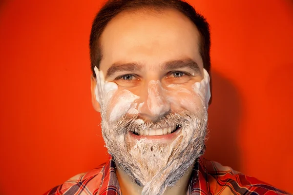 Handsome man with shaving foam on his face and razor
