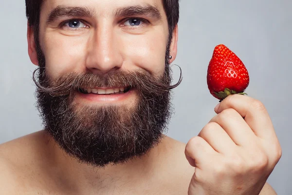 Close-up portrait young man holding a strawberry and smiling