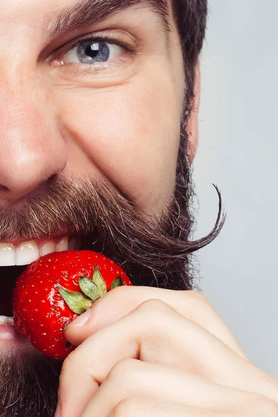 Close-up portrait young man holding a strawberry and smiling