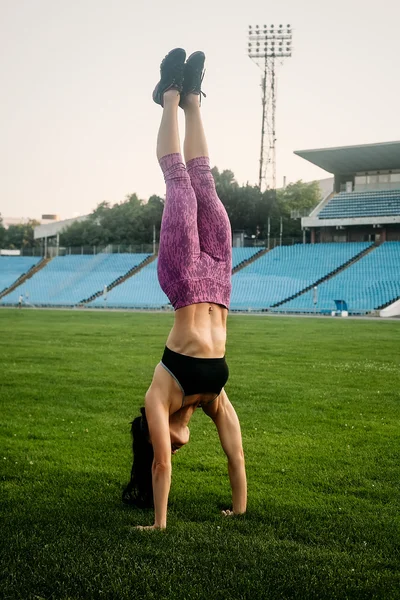 Slim athletic woman with dumbbells in the stadium