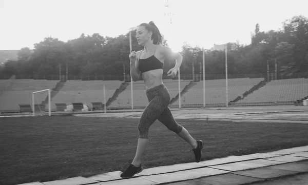 Slim athletic woman with dumbbells in the stadium