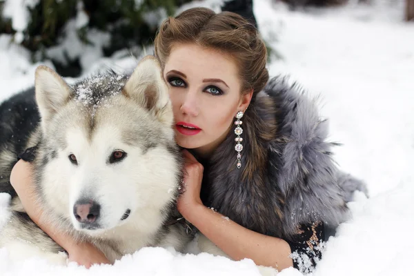 Young woman with wolf dog in snow