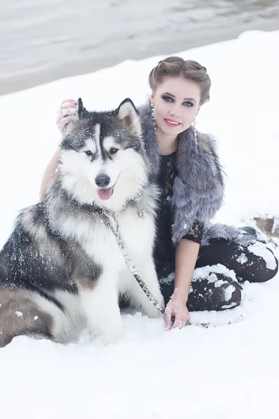 Young woman with wolf dog in snow